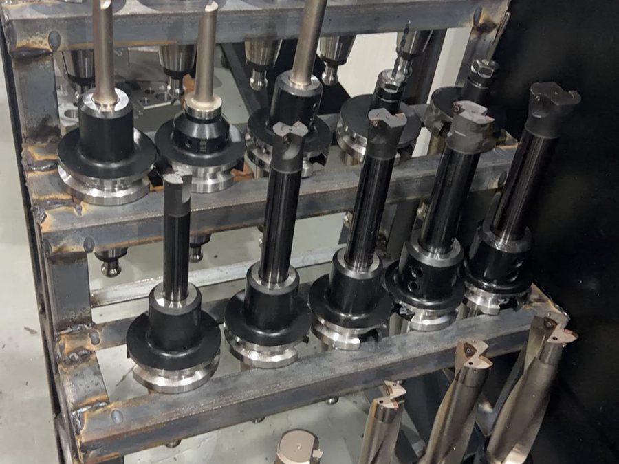 Tool rack holding milling cutters and boring bars beside a machining centre